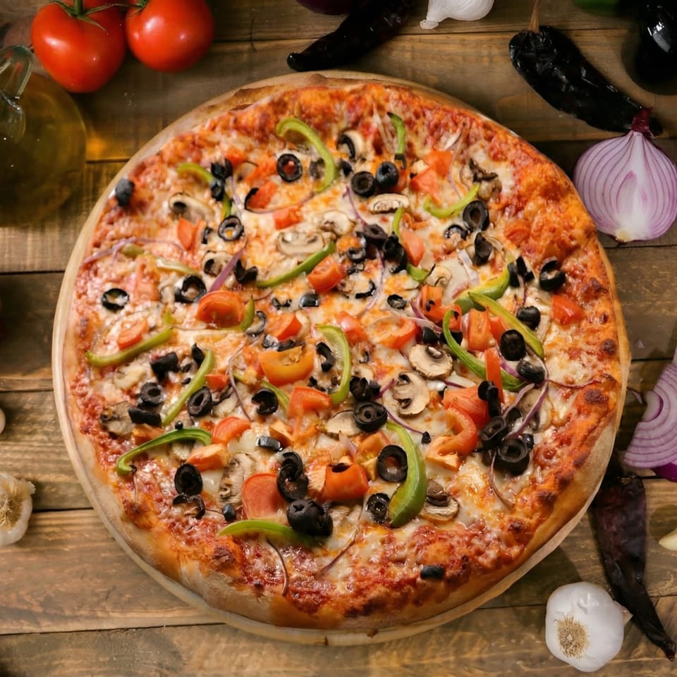 A large, round pizza with olives, green peppers, mushrooms, and tomatoes on a wooden table.